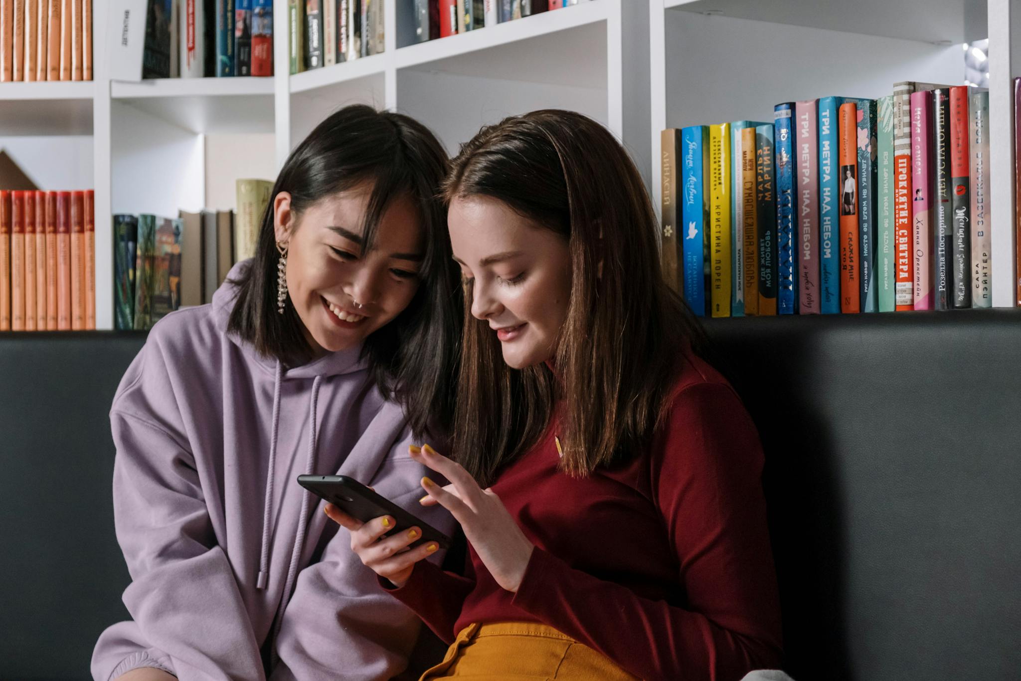 A Girl in Red Sweater Holding Her Phone while Talking to Her Friend